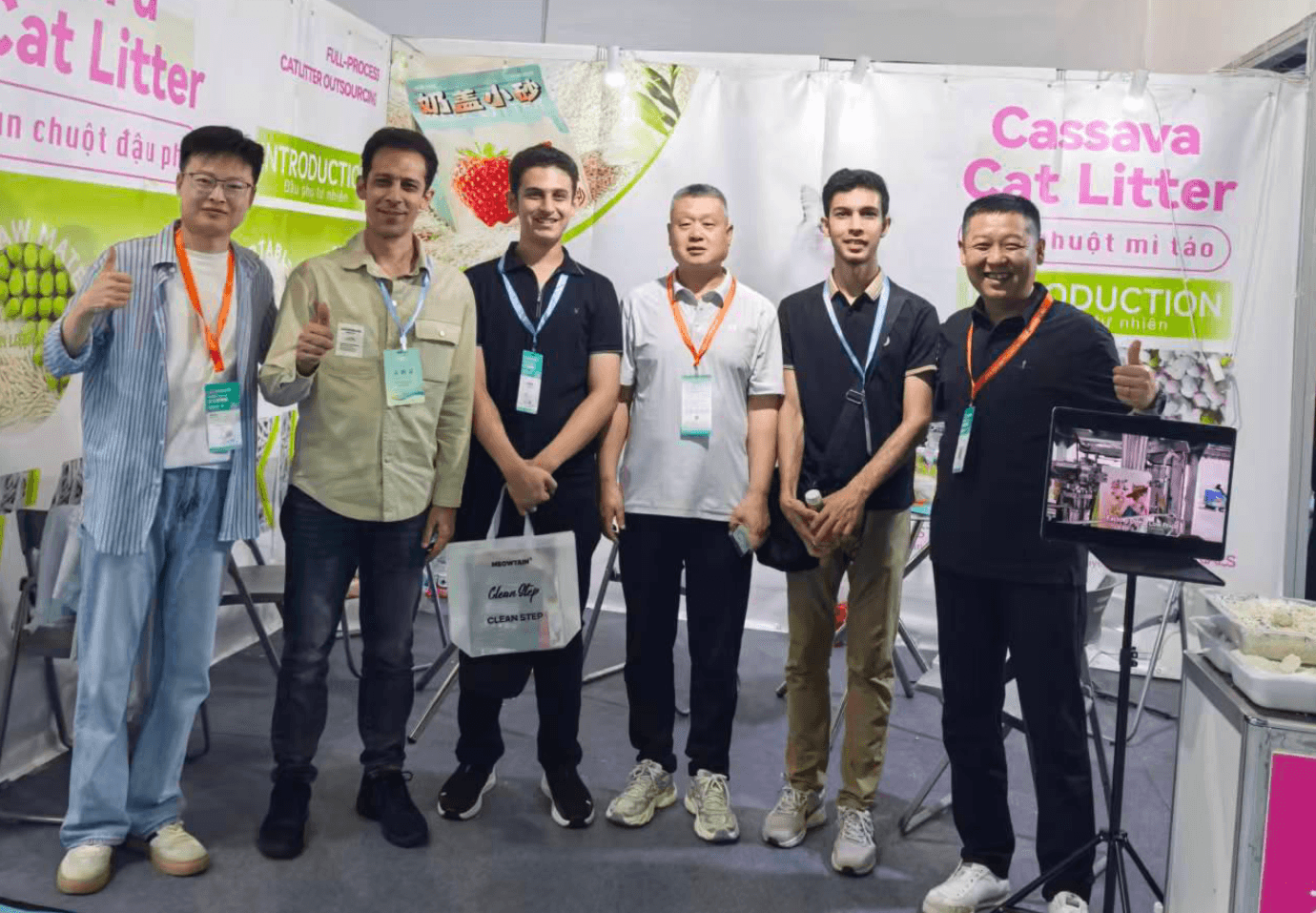 Six international buyers visiting the RootPurr trade-show booth, in front of the ToFu Cat Litter / Cassava Cat Litter backdrop.