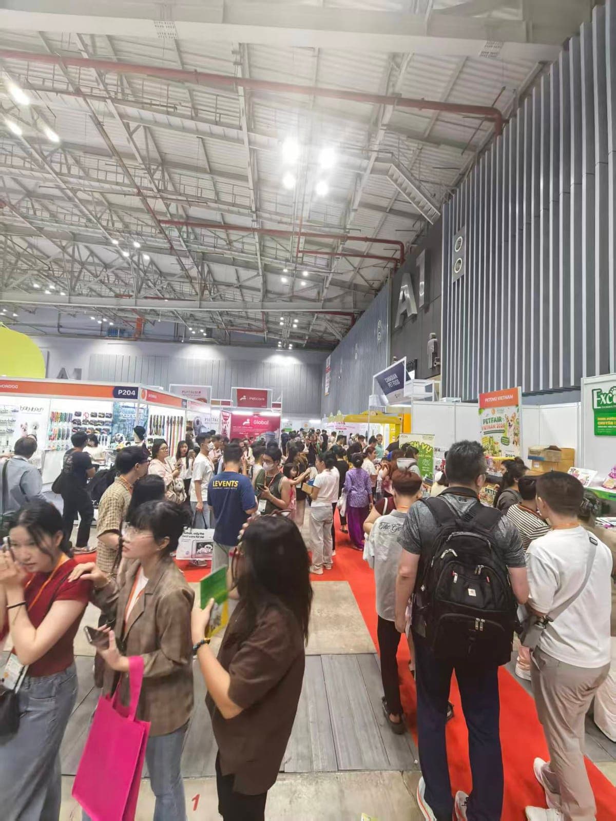 Crowded exhibition floor at Petfair Vietnam 2026 — importers and distributors touring the pet-industry booths.