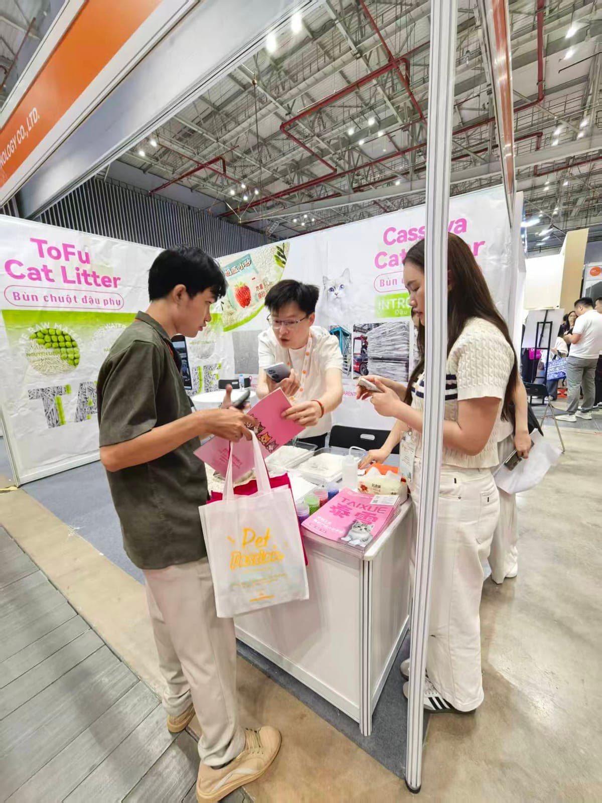 A buyer at the RootPurr ToFu Cat Litter booth, Petfair Vietnam 2026, reviewing the plant-based litter range with a RootPurr representative.